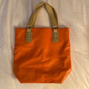 Faux leather orange hand bag with a pink interior.